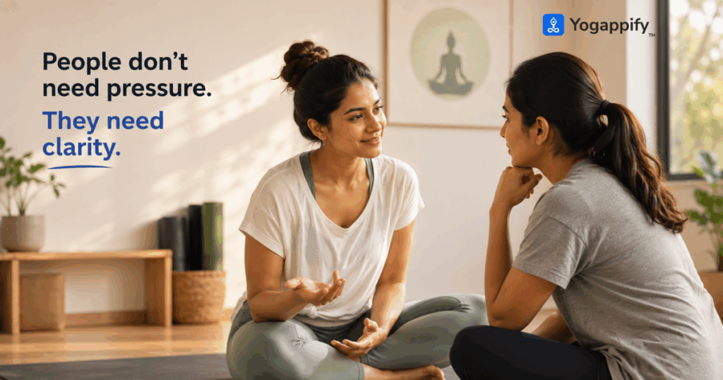 Yoga teacher having a calm conversation with a prospective student to answer questions and build confidence before joining a yoga class.